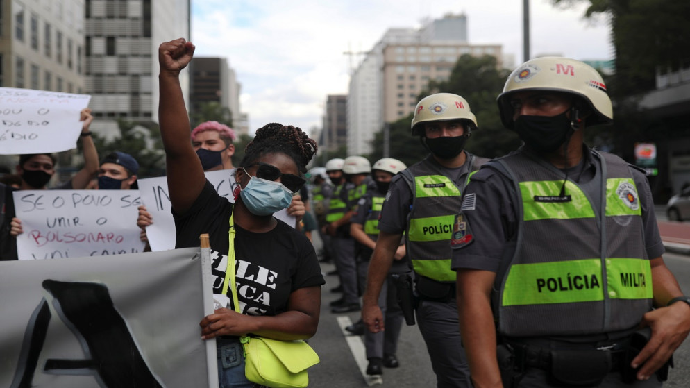 متظاهرون يقفون بجانب ضباط شرطة خلال احتجاج ضد الرئيس البرازيلي جايير بولسونارو وتعامله مع تفشي كوفيد-19 في ساو باولو، البرازيل، 31 كانون الثاني/ يناير 2021. (رويترز)