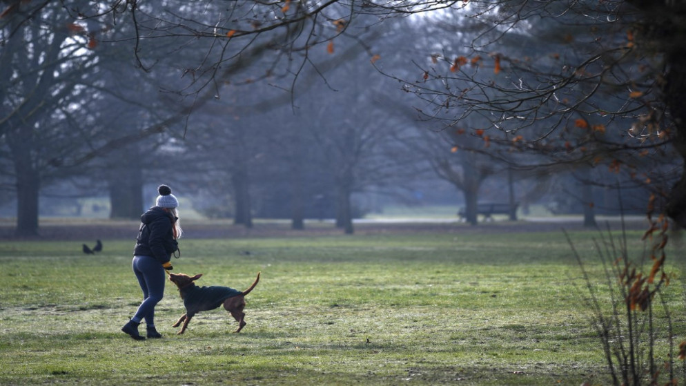 امرأة تلعب مع كلبها وهي تمارس تمرينها اليومي في غرينتش بارك، جنوب شرق لندن، 23 كانون الثاني/يناير 2021. (أ ف ب)