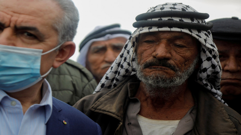 رجل يقف بجانب رئيس الوزراء الفلسطيني محمد اشتية خلال زيارة لقرية خربة حمصة في غور الأردن بالضفة الغربية المحتلة التي دمرها جيش الاحتلال الإسرائيلي،4 شباط/فبراير 2021. (رنين صوافطة/ رويترز)