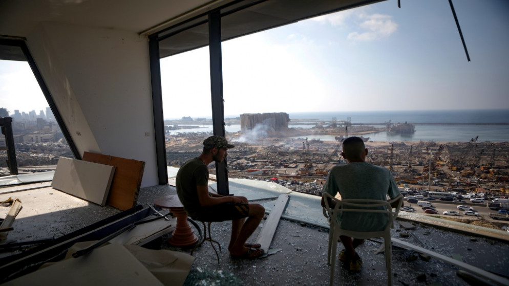رجلان ينظران إلى ميناء بيروت المدمر من مبنى مدمر في حي مار مكايل القريب ، بعد يومين من انفجار ضخم هز العاصمة اللبنانية.6 أغسطس ، 2020. (أ ف ب)