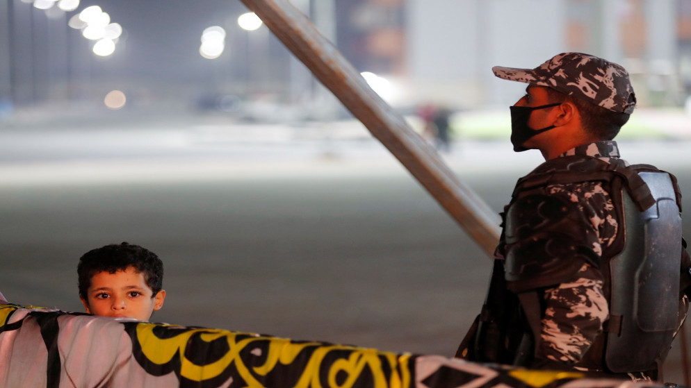 شرطي مصري يرتدي قناعًا واقياً بينما يشاهد طفل فرقة موسيقية تقدم عرضًا في مسرح متنقل وسط جائحة فيروس كورونا (COVID-19) في القاهرة. مصر .30 يناير 2021. (رويترز)