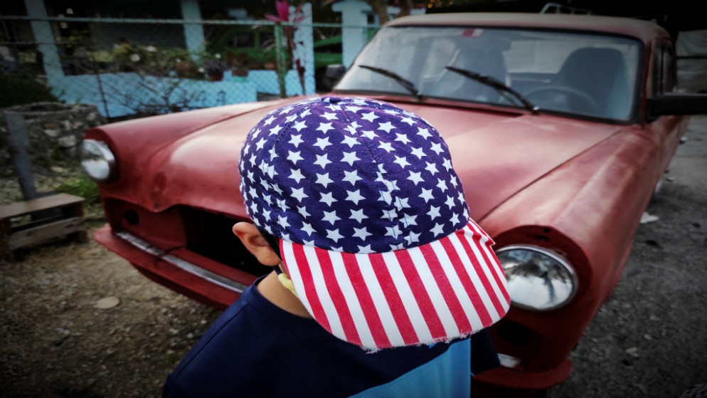 طفل يرتدي قبعة تحمل العلم الأميركي على طول أحد شوارع هافانا .26 يناير 2021.(أ ف ب)