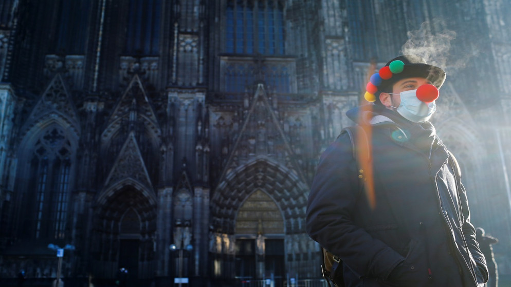 محتفل وحيد أمام كاتدرائية كولونيا بعد إلغاء احتفالات الكرنفال بسبب جائحة فيروس كورونا (COVID-19)، كولونيا، ألمانيا، 11 شباط/ فبراير 2021. (رويترز)