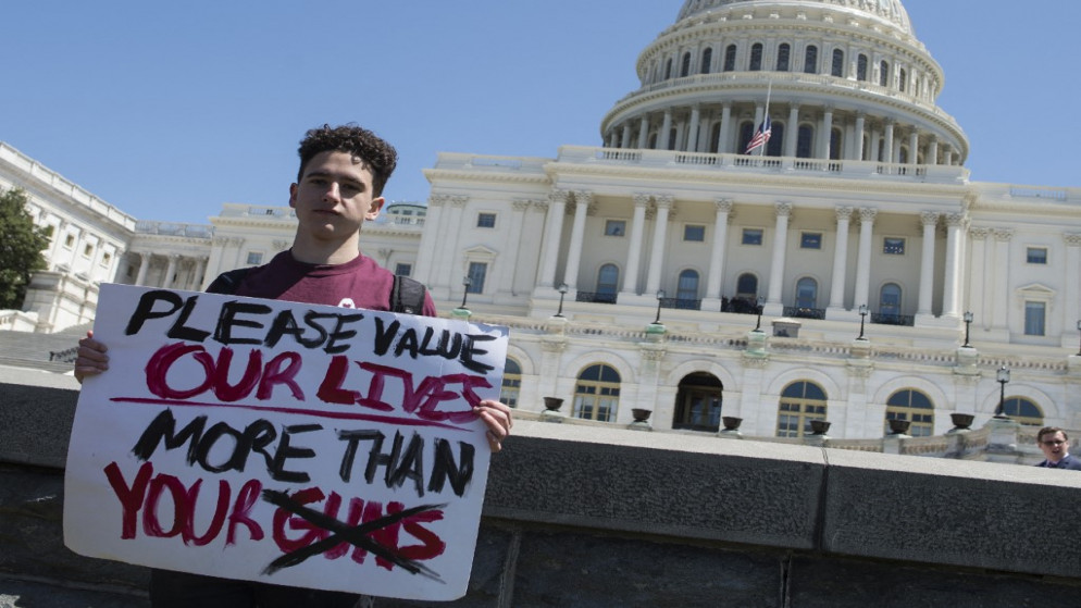 فتى يقف ومن خلفه مبنى الكابيتول للمطالبة بتشديد في قوانين بيع السلاح في الولايات المتحدة. (أ ف ب)