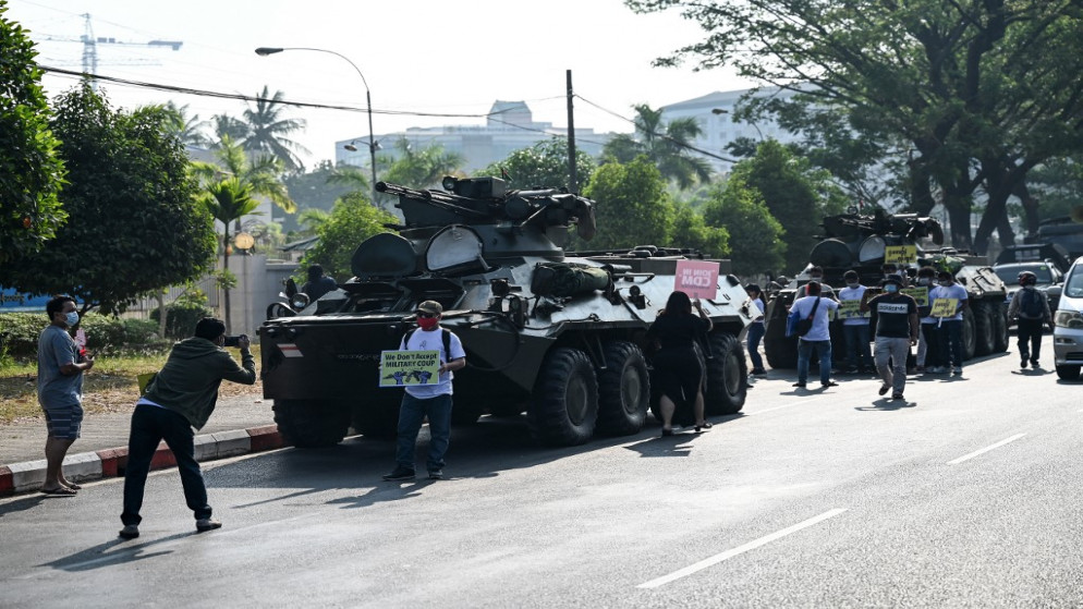 تجمع المتظاهرون بجوار المركبات العسكرية المتوقفة على طول شارع في وسط مدينة يانغون، 15 شباط/ فبراير 2021. (أ ف ب)