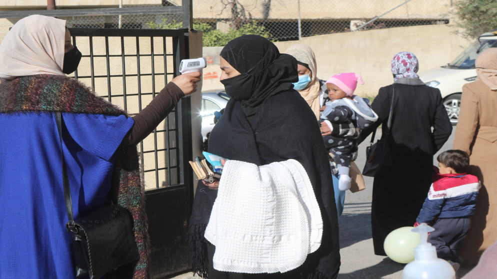 استخدام جهاز قياس الحرارة قبل الدخول إلى مدرسة في عمّان. (صلاح ملكاوي/المملكة)