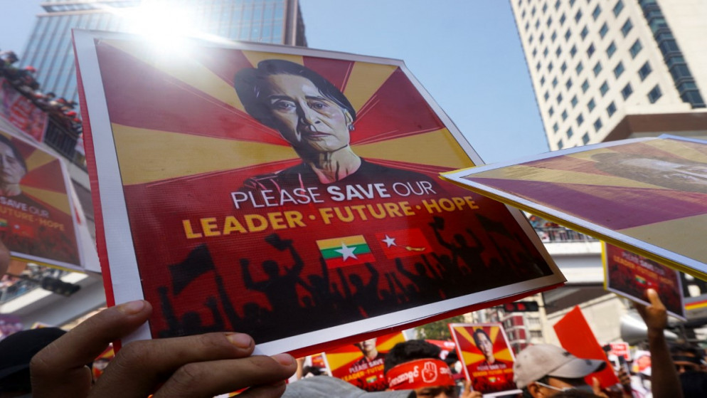 متظاهرون يحملون لافتات عليها صورة أونغ سان سو كي أثناء مشاركتهم في تظاهرة ضد الانقلاب العسكري في يانجون .22 فبراير 2021.(أ ف ب)