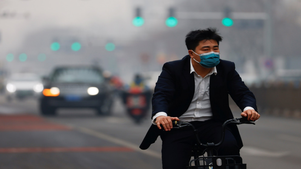 رجل يرتدي كمامات للوقاية من فيروس كورونا المستجد ويقود دراجته في شارع عام في بكين.13/02/2021. (كارلوس جارسيا رولينز/ أ ف ب)