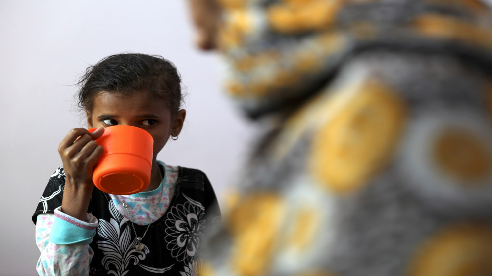 أحمدية الجعيدي طفلة يمنية وهي تحتسي مشروبا من كوب برتقالي تمسك به. (رويترز)