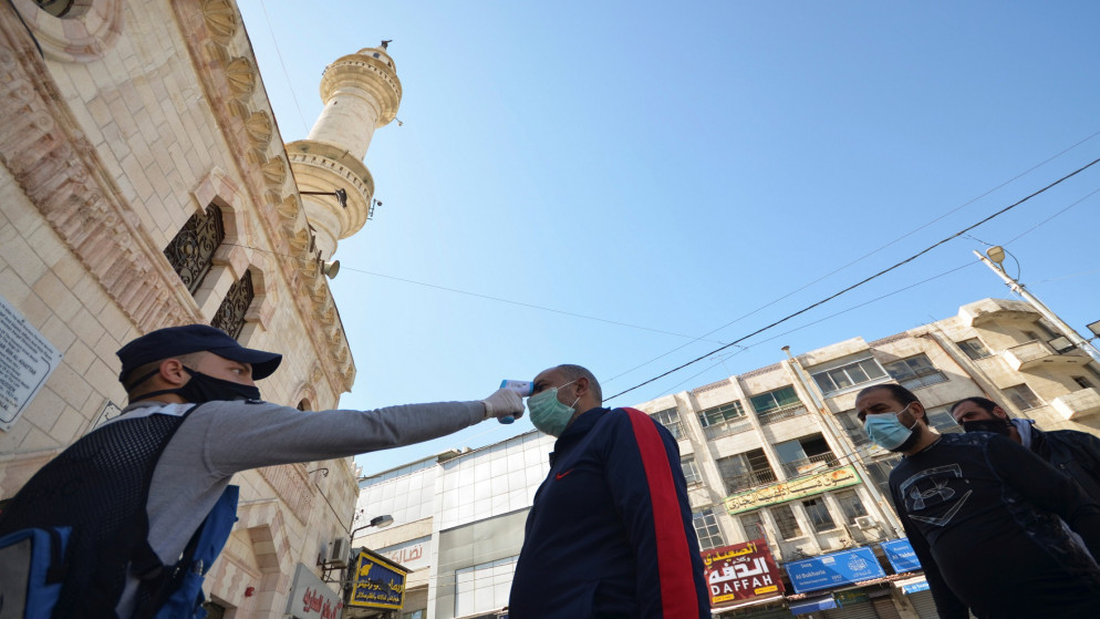 عناصر من الدفاع المدني يتحققون من درجة حرارة المصلين قبل صلاة الجمعة خارج المسجد الحسيني، 26 شباط/فبراير 2021. (رويترز / معاذ فريج)
