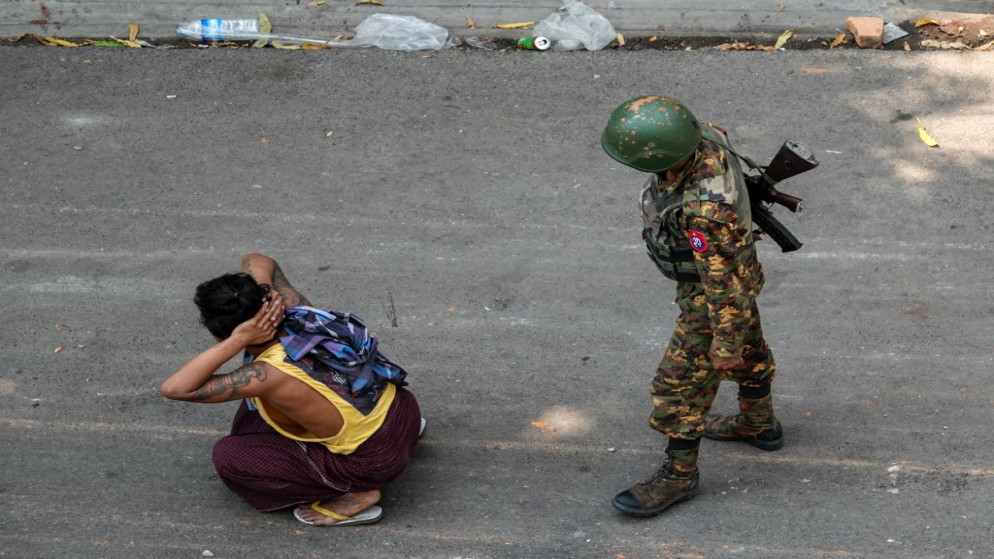 جندي يقف بجانب رجل معتقل خلال تظاهرة ضد الانقلاب العسكري في ماندالاي في 3 مارس/آذار 2021.