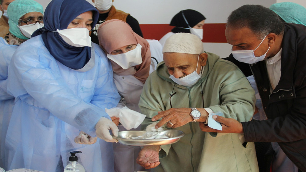 عاملون في مجال الرعاية الصحية يساعدون رجلاً مسنًا بعد تلقيه لقاح كورونا، سلا، المغرب، 29 شباط/ يناير 2021. (رويترز)