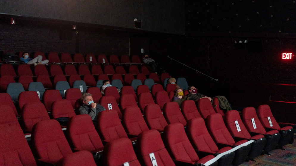 رواد السينما الذين يرتدون كمامات واقية يجلسون في مقاعد بعيدة اجتماعيًا في مسرح السينما بمركز IFC وسط جائحة فيروس كورونا في حي مانهاتن، نيويورك 5 آذار/ مارس 2021. (رويترز)