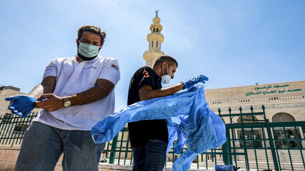 صورة أرشيفية لعضوي فريق طبي يستعدان لإجراء فحوص الكشف عن فيروس كورونا المستجد في عمّان. (أ ف ب)