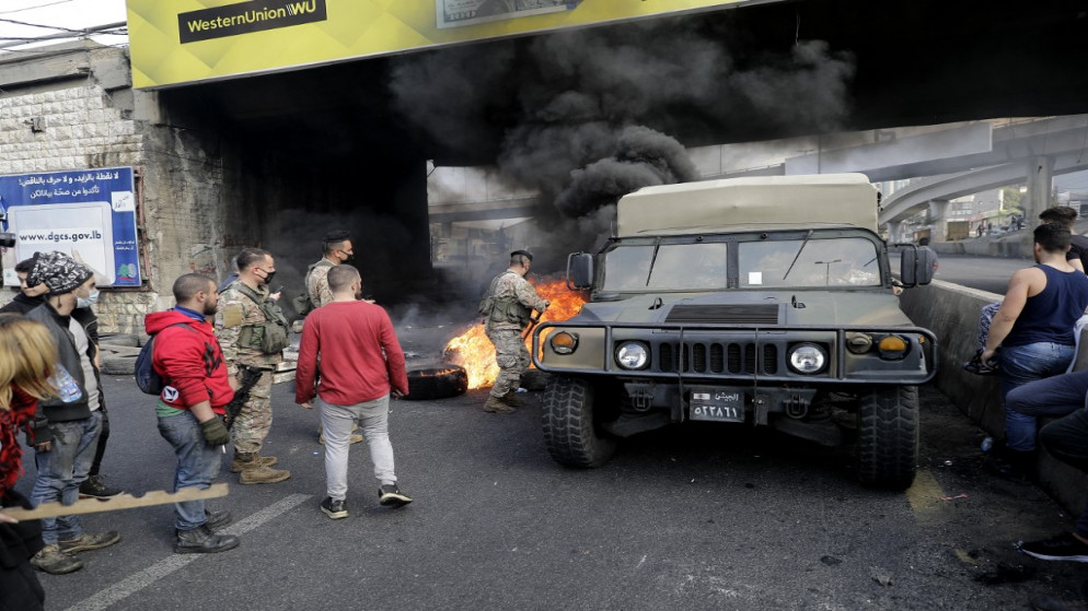 قوات من الجيش اللبناني تحاول إزالة النيران عن الشارع وسط تظاهرات في لبنان. (أ ف ب)