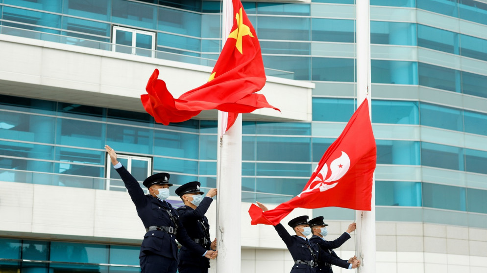 ضباط شرطة يشيرون إلى جانب علمي الصين وهونغ كونغ في حفل رفع العلم، ميدان بوهينيا الذهبي، هونغ كونغ، الصين، 11 آذار/ مارس 2021. (رويترز) (رويترز) / Tyrone Siu TPX IMAGES OF THE DAY