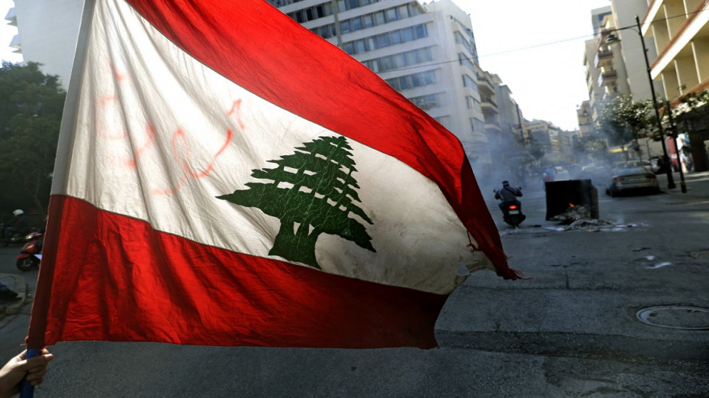 متظاهر مناهض للحكومة يلوح بالعلم اللبناني في العاصمة بيروت في 16 آذار/مارس 2021 (أ ف ب)
