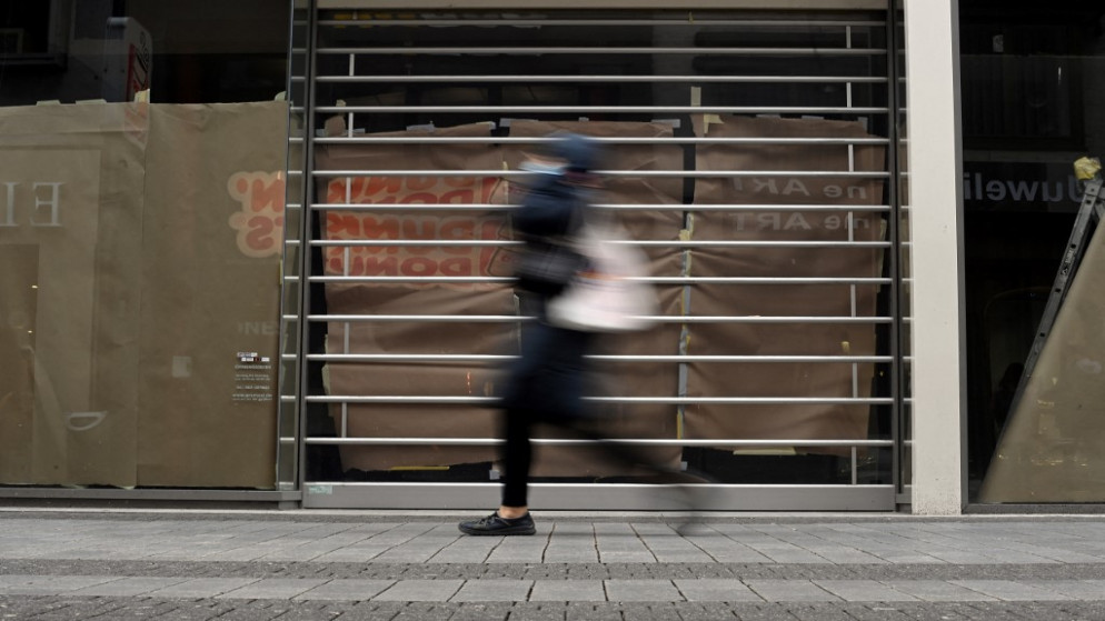 امرأة تسير أمام متجر مغلق في مدينة كولونيا غربي ألمانيا. (أ ف ب)