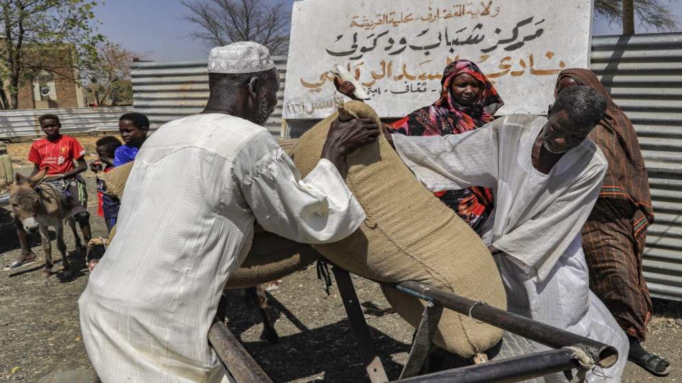 رجال يفرغون كيسًا من الحبوب في منطقة الفشقة الصغرى بولاية القضارف شرق السودان .16 مارس / آذار 2021. (أ ف ب)
