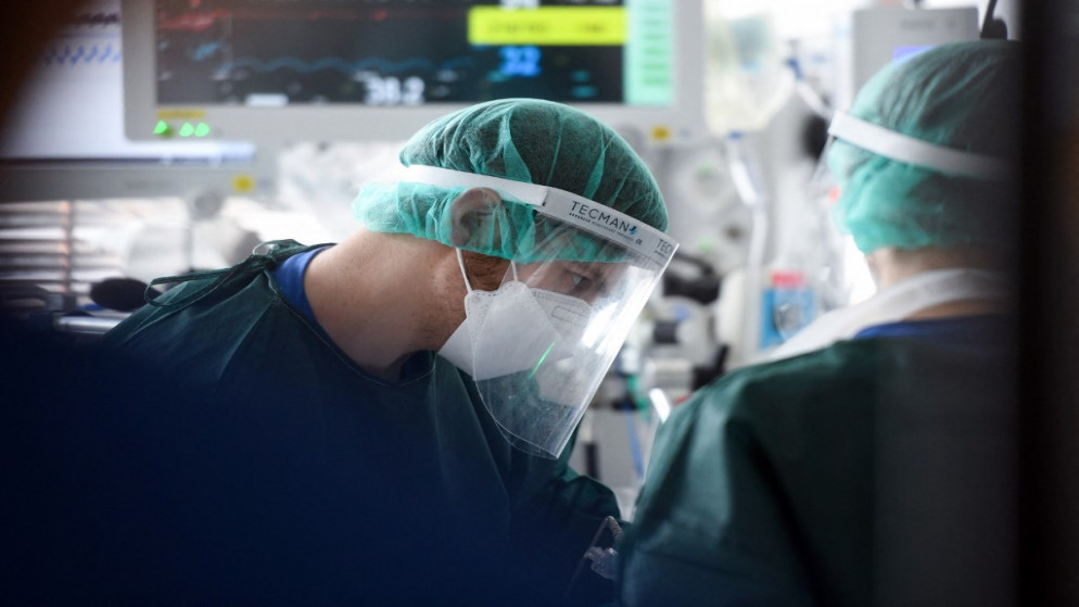 ممرض يعتني بمريض مصاب بفيروس كورونا في وحدة العناية الحثيثة في مستشفى جامعي في إيسن، غرب ألمانيا، 22 آذار/مارس 2021 (أ ف ب)