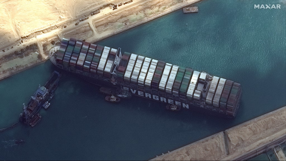 قوارب تحاول تحرير السفينة الجانحة في قناة السويس. (أ ف ب)