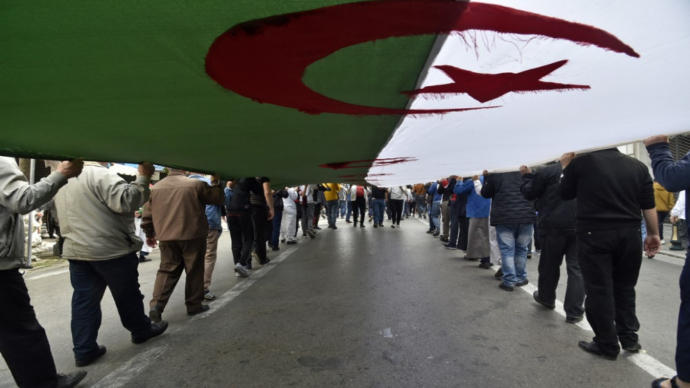 جزائريون يرفعون علما وطنيًا عملاقًا خلال تظاهرة مناهضة للحكومة في العاصمة الجزائرية، 2 نيسان/أبريل 2021. (أ ف ب)