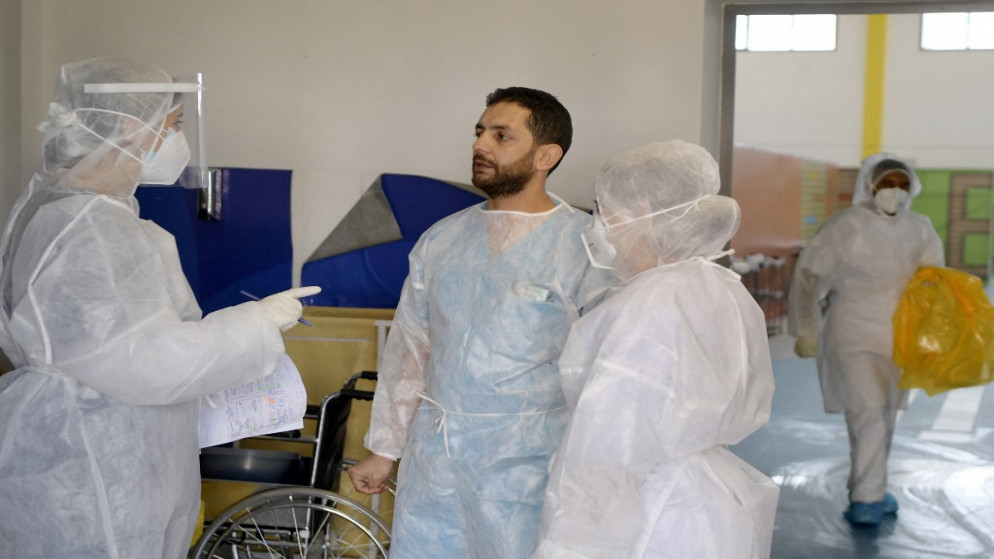 طبيب الطوارئ التونسي عبد الوهاب مغربي ، 35 عامًا ، يتحدث إلى طاقم خدمة COVID-19 التابع لمستشفى مامي في مدينة أريانة بالقرب من العاصمة .12 آذار/مارس 2021.(أ ف ب)