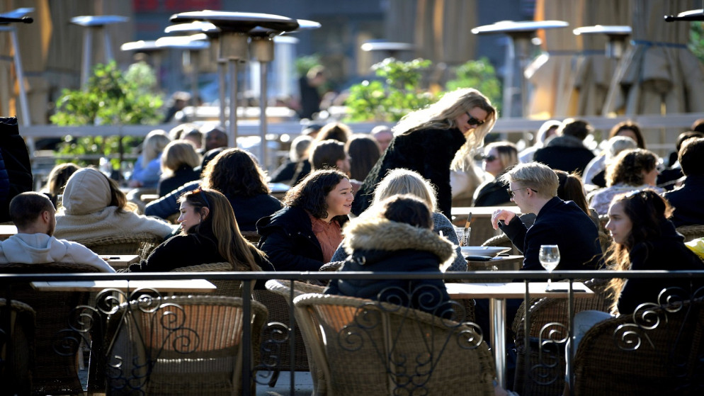 يستمتع الناس بالشمس في مطعم في الهواء الطلق، على الرغم من استمرار انتشار مرض الفيروس كورونا، في ستوكهولم، السويد ، 26 آذار/ مارس 2020. (رويترز)