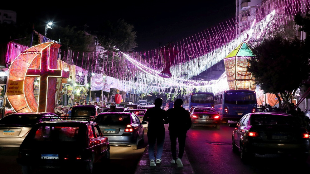 أشخاص يسيرون في الشارع أمام كشك متجر به فوانيس رمضان التقليدية، قبل حلول شهر رمضان المبارك، وسط جائحة كورونا، القاهرة، مصر ، 8 أبريل 2021. (رويترز)