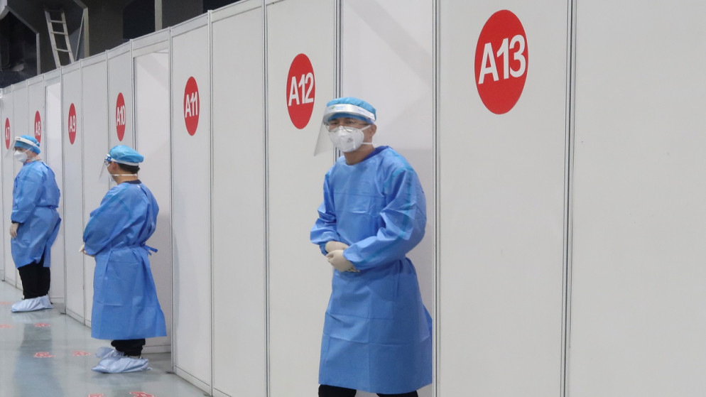 ينتظر الموظفون خارج الأكشاك حيث يتلقى الناس لقاحًا ضد فيروس كورونا، في مركز التطعيم، بكين، الصين، 15 نيسان/ أبريل 2021. (رويترز)