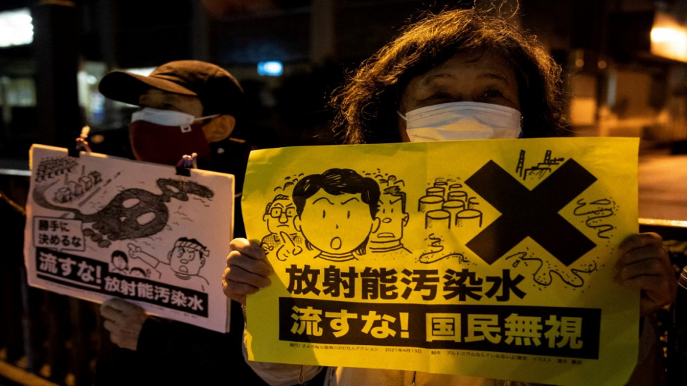 متظاهرة تحمل شعارًا كتب عليه باللغة اليابانية "لا تطلقوا المياه المشعة" خلال مسيرة ضد قرار الحكومة اليابانية بإطلاق المياه المعالجة من محطة فوكوشيما دايتشي النووية المنكوبة في البحر .طوكيو . 13 أبريل/نيسان 2021. (يوكي إيوامورا / أ ف ب)