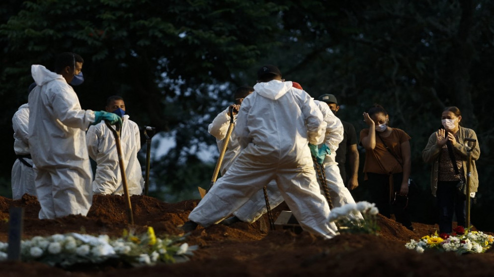 أشخاص يودعون أقاربهم وهم يرتدون معدات واقية كإجراء وقائي ضد انتشار فيروس كورونا، في مقبرة فيلا فورموزا في ساو باولو، البرازيل. (أ ف ب)