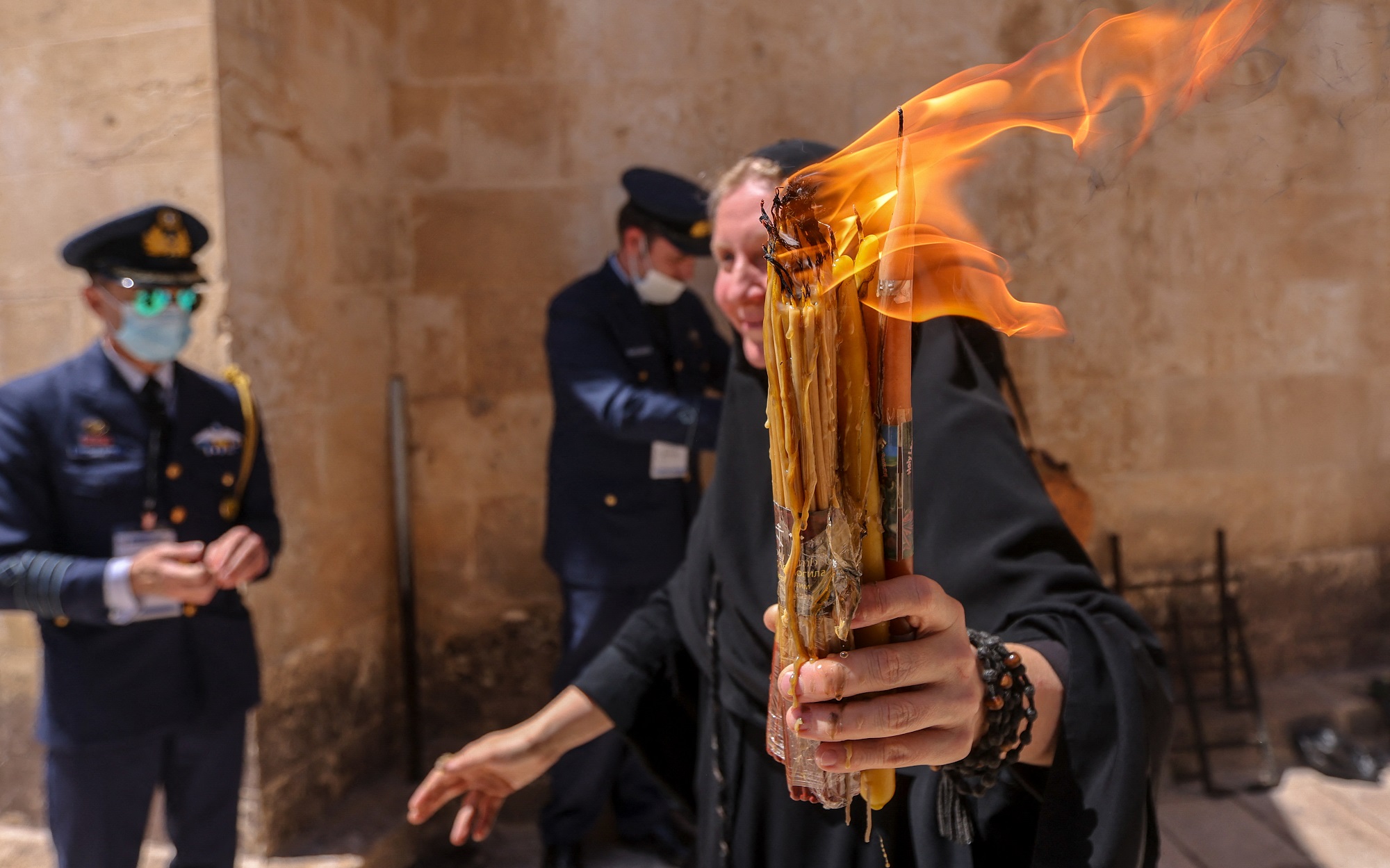 راهبة تمشي مع شموعها المضاءة في باحة كنيسة القيامة في القدس. 1 مايو 2021. (أ ف ب)