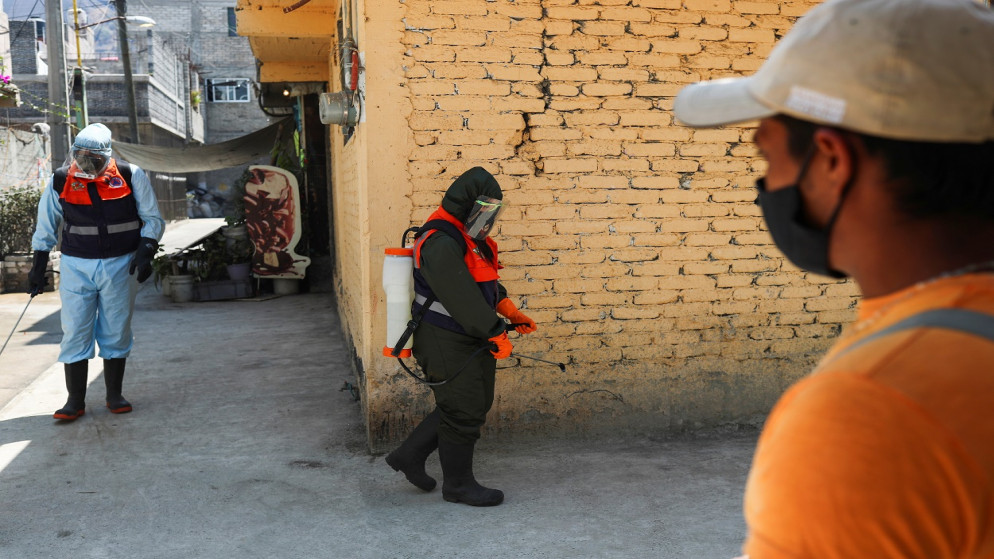 أفراد الحماية المدنية يرشون مطهرًا خارج منزل مع استمرار تفشي الفيروس، في حي إيزتابالابا في مكسيكو سيتي ، المكسيك ، 11 آذار/ مارس 2021. (رويترز)