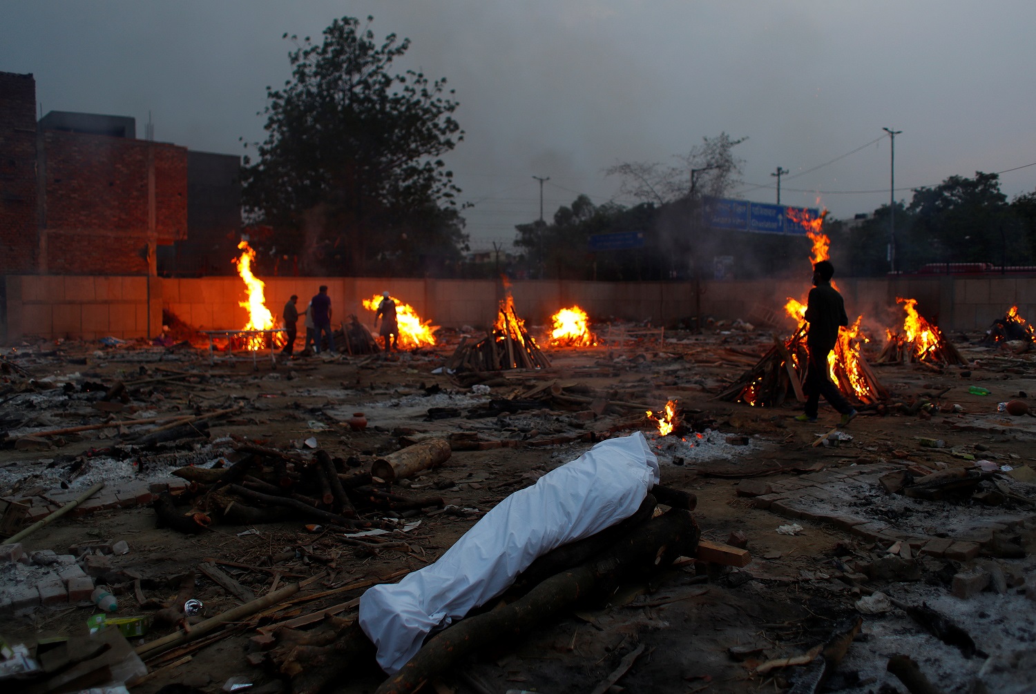 رجل يمر بجوار محرقة جنائزية لشخص مات بسبب فيروس كورونا (كوفيد -19) ، خلال حرق جماعي في محرقة جثث في نيودلهي ، الهند ، 1 مايو/أيار 2021. (رويترز / عدنان عبيدي)