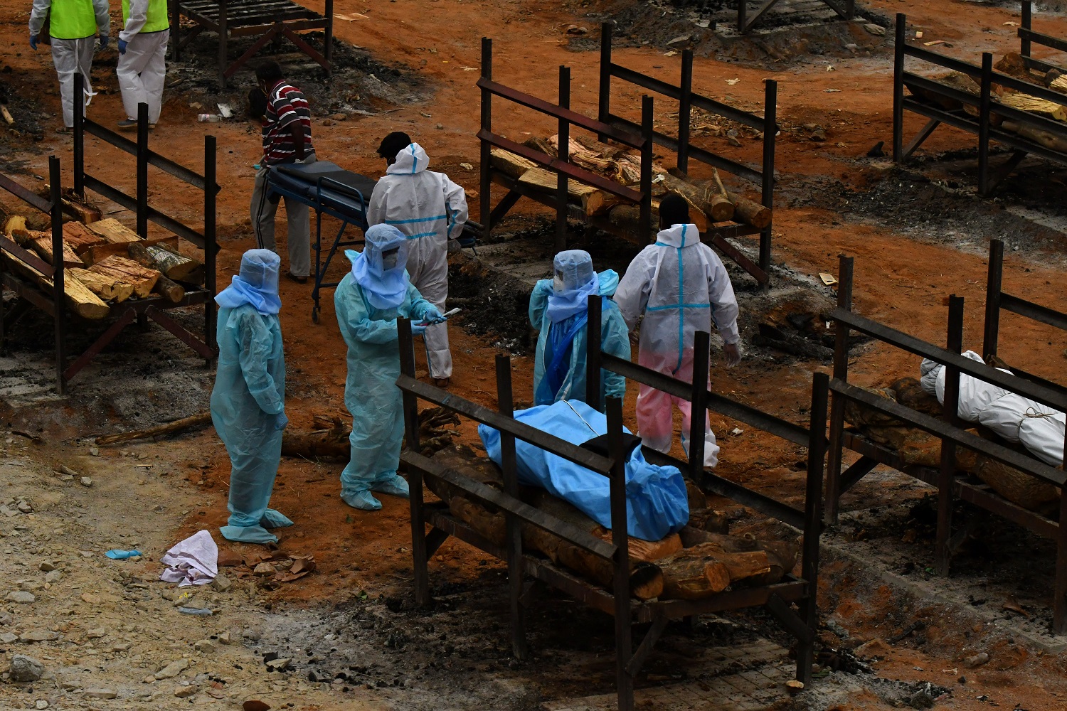 متطوعون وأقارب يستعدون لحرق جثث الأشخاص الذين لقوا حتفهم بسبب مرض فيروس كورونا في محرقة جثث في قرية جيدينهالي في ضواحي بنغالورو ، الهند ، 2 مايو 2021. (رويترز)