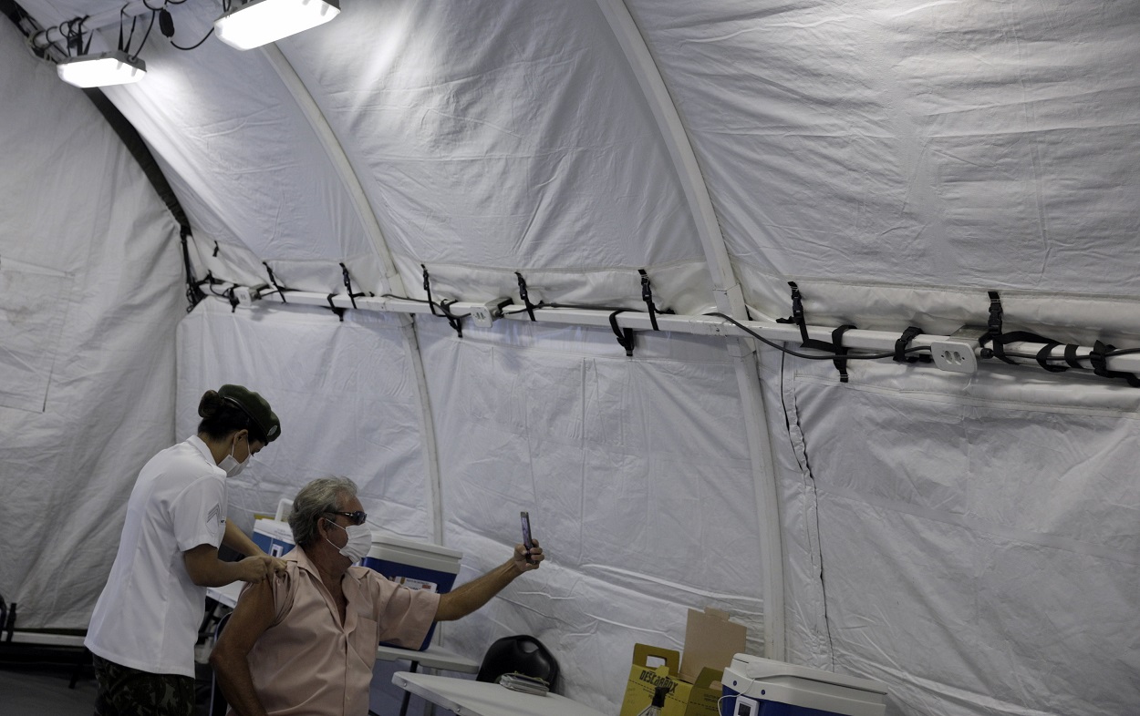 ممرضة في الجيش البرازيلي، تعطي مواطن جرعة من لقاح كورونا، في خيمة للقوات المسلحة البرازيلية، وسط مدينة ريو دي جانيرو، البرازيل، 3 أيار/مايو 2021. (رويترز )