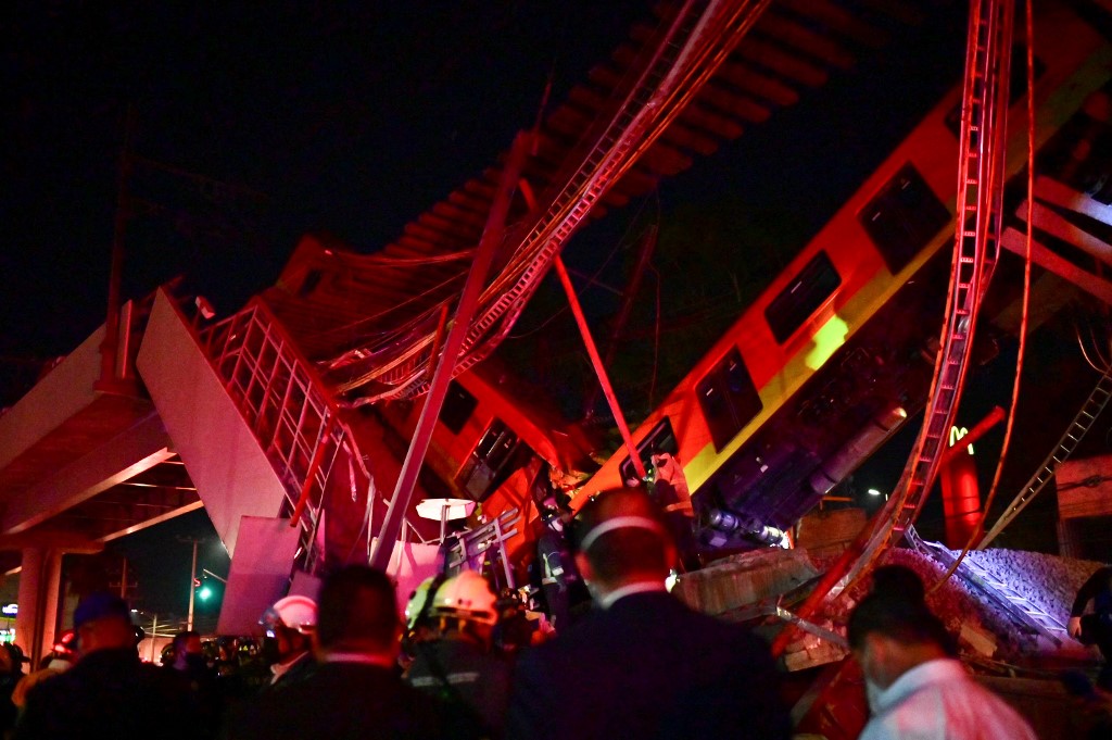 عمال الإنقاذ يتجمعون في موقع حادث قطار مترو بعد انهيار جسر علوي لمترو جزئيًا في مكسيكو في 3 مايو 2021. (أ ف ب)
