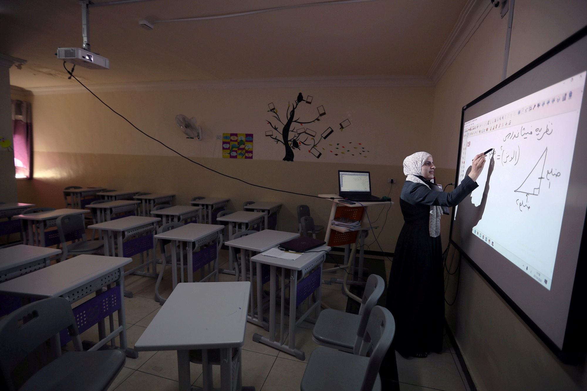 معلمة تعطي دروسا لطلابها عن بعد من أحد الغرف الصفية في إحدى مدارس عمّان. (رويترز)