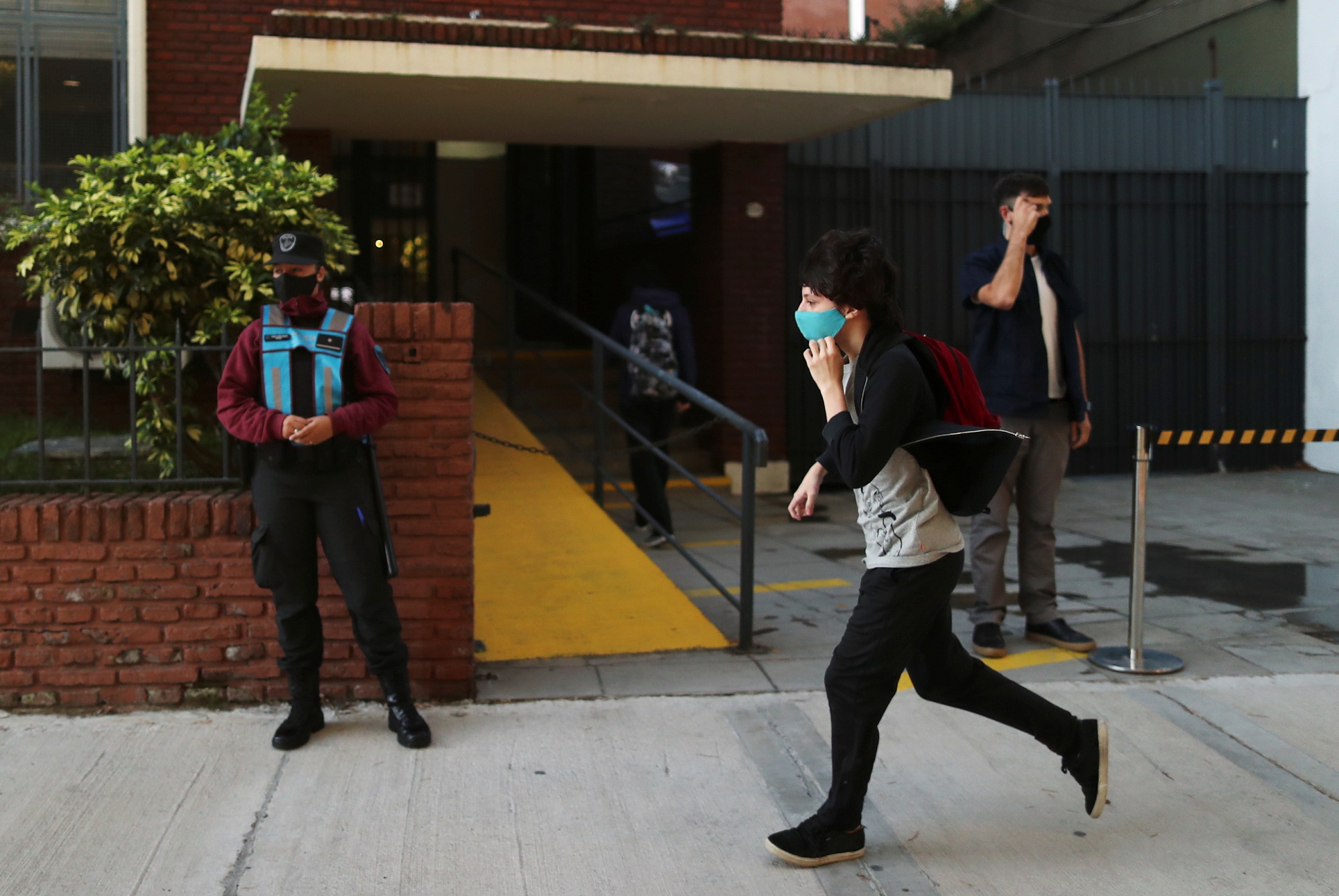 وصول طالب إلى مدرسة في الأرجنتين وسط تطبيق قواعد التباعد الجسدي ولبس الكمامة. (رويترز)