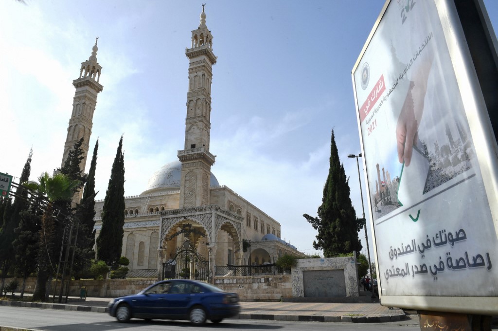 لافتة تدعو الناس إلى التصويت أمام مسجد في مدينة حلب شمال سوريا .3 مايو / أيار 2021. (أ ف ب)