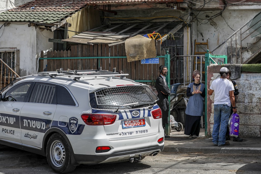 شرطية إسرائيلية تتحدث مع مستوطنين يهود خارج المنزل الذي استولوا عليه من عائلة فلسطينية في عام 2009 ، في حي الشيخ جراح في القدس الشرقية . 6 مايو ، 2021. (أ ف ب)