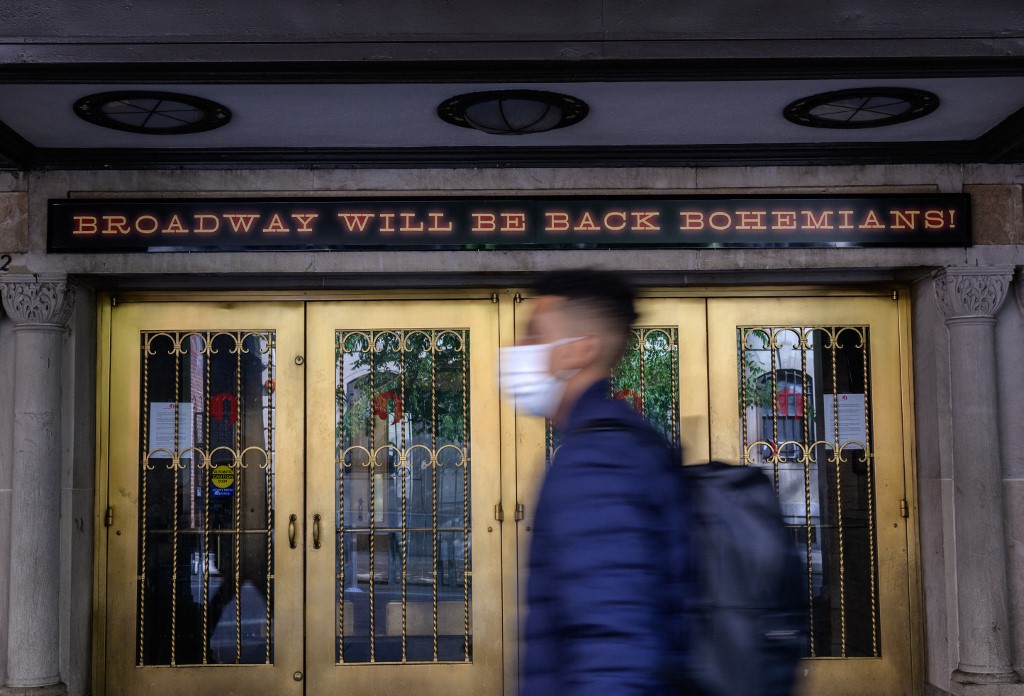 أشخاص يسيرون أمام مسرح برودواي المغلق في مدينة نيويورك. الذي من المتوقع إعادة افتتاحه في 14 سبتمبر/أيلول 2021 بسعة 100%. 06/05/2021. (أنجيلا وايس /أ ف ب)
