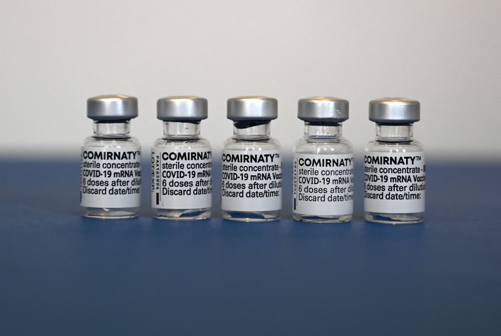 قوارير مستعملة من لقاح فايزر-بيونتيك المضاد لفيروس كورونا بجانب بطاقة تطعيم في عيادة طبيب في ألمانيا. 06/05/2021. (كريستوف ستاتش / أ ف ب)