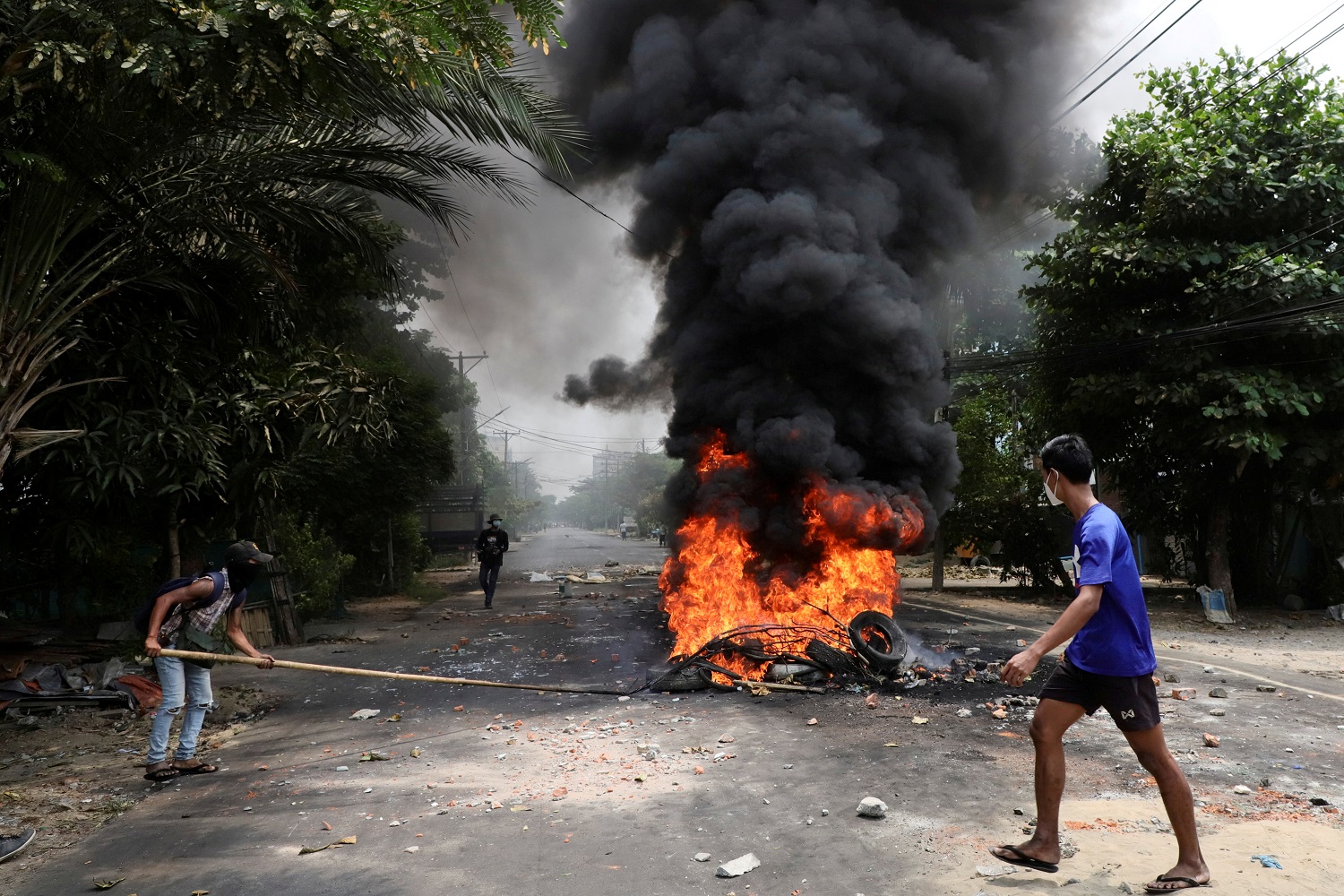 متظاهر مناهض للانقلاب يمشي بالقرب من إطارات محترقة في يانغون . ميانمار .30 مارس / آذار 2021.(رويترز)