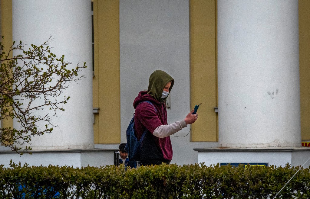 رجل يرتدي قناعا للوجه يحمل هاتفا خلويا أثناء سيره في وسط موسكو .30 أبريل 2021. (يوري كادوبنوف / أ ف ب)