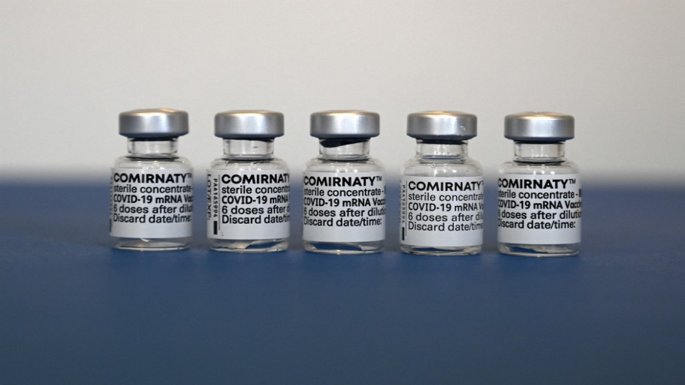 قوارير مستعملة من لقاح فايزر-بيونتيك المضاد لفيروس كورونا بجانب بطاقة تطعيم في عيادة طبيب في ألمانيا. 06/05/2021. (كريستوف ستاتش / أ ف ب)