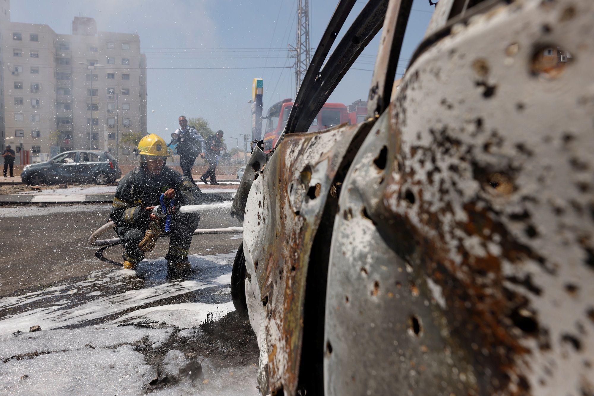 رجل إطفاء إسرائيلي يطفئ مركبة اشتعلت فيها النيران بعد إطلاق صاروخ من قطاع غزة على عسقلان. 11/05/2021. (رويترز)