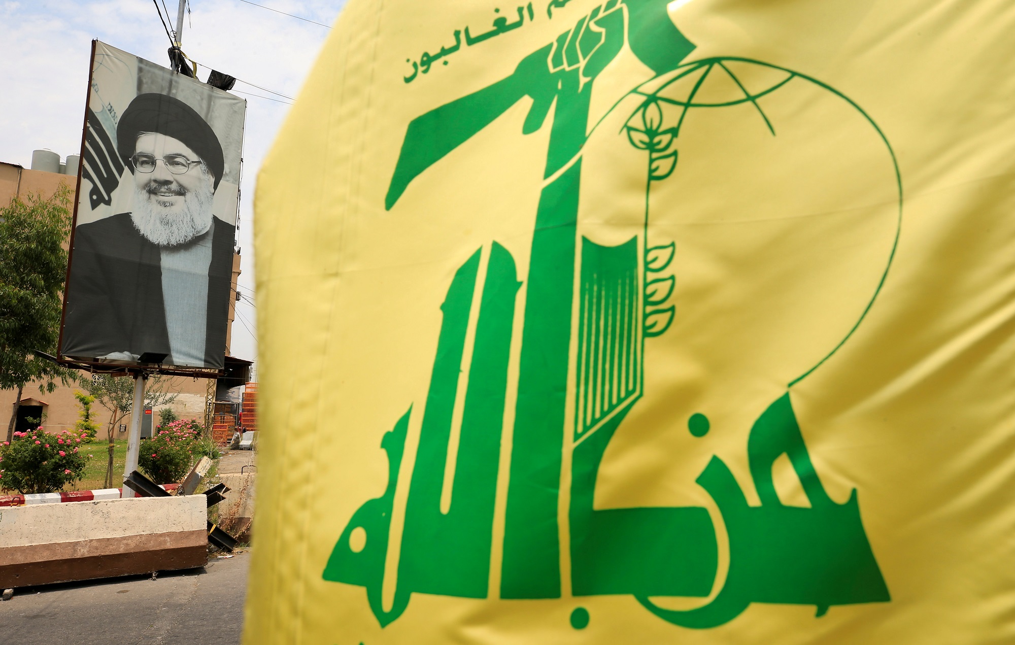 صورة لعلم جماعة حزب الله في إيران ومن خلفه صورة لحسن نصر الله الأمين العام للحزب. (رويترز)
