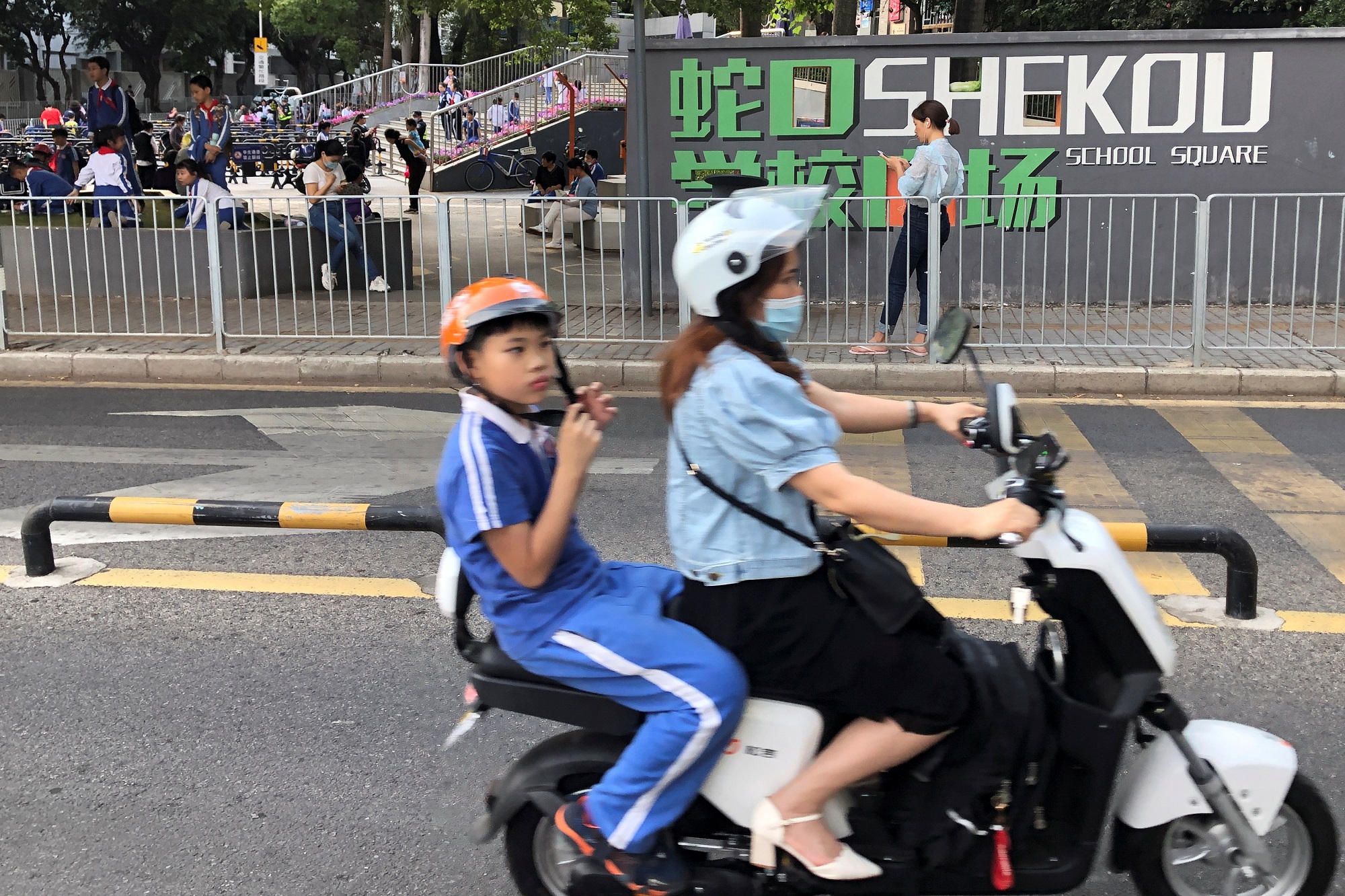 امرأة تقود دراجة لإيصال طفلها إلى مدرسة في الصين. (رويترز)